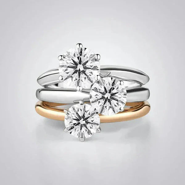 A elegant stack of solitaire diamond rings from the TM & Co. Jewels collection, featuring a mix of precious metal bands.