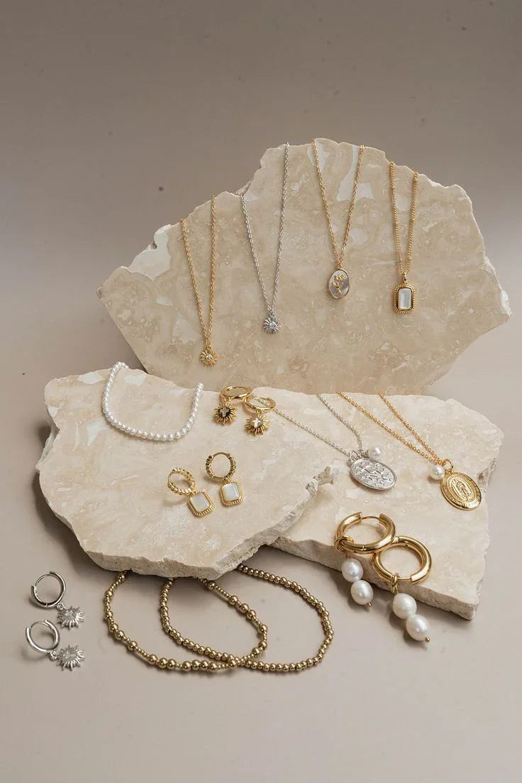 Collection of gold and pearl jewelry on a stone surface