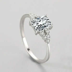 Elegant silver ring with a princess-cut center stone and small round accent gems