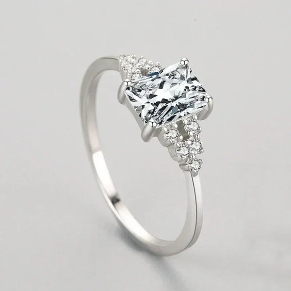 Elegant silver ring with a princess-cut center stone and small round accent gems