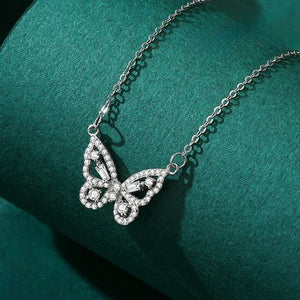Butterfly Bliss Necklace - TM & CO. JEWELS - Silver butterfly necklace on a green cushion.