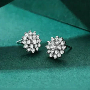 Pair of silver floral earrings with clear stones on a green textured background