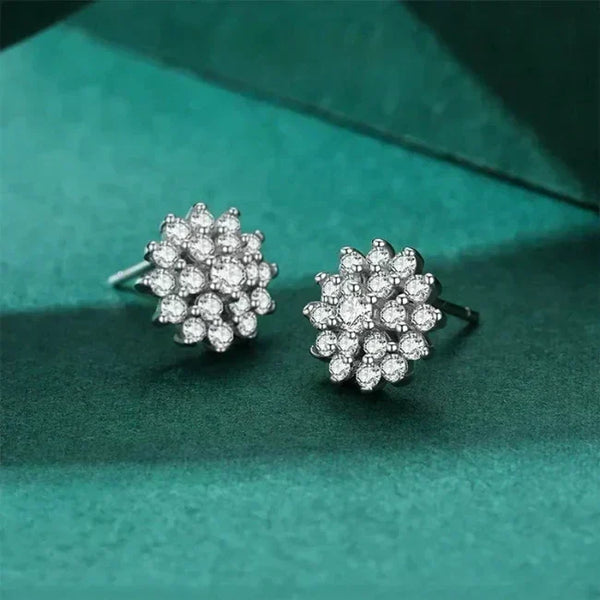 Pair of silver floral earrings with clear stones on a green textured background