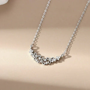 Silver necklace with floral design on a beige background.