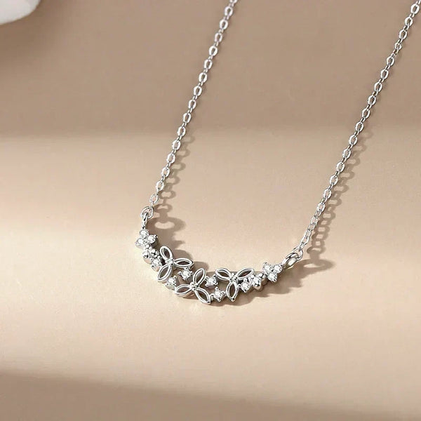 Silver necklace with floral design on a beige background.