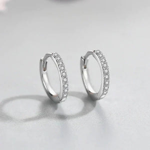 Silver hoop earrings with embedded stones on a light gray background