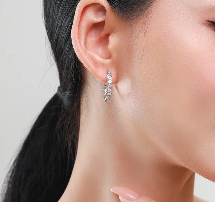 Close-up of an ear wearing a sparkling earring with a neutral background
