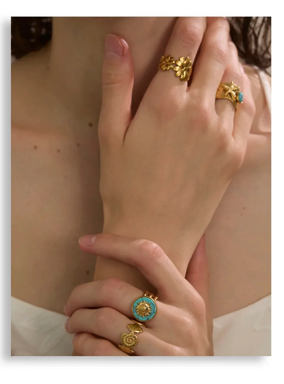Close-up of a hand wearing gold rings with turquoise stones.