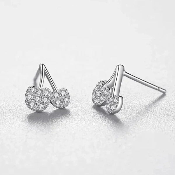 Pair of silver earrings with clear gemstones on a light gray background