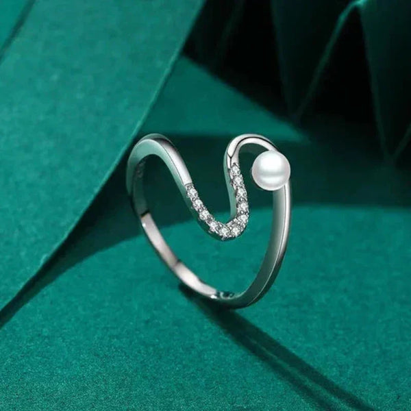 Silver ring with a pearl on a green fabric background
