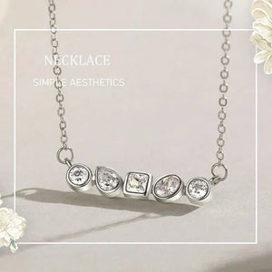 Silver necklace with five diamond pendants on a light gray background