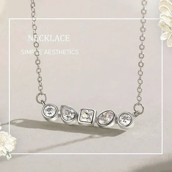 Silver necklace with five diamond pendants on a light gray background