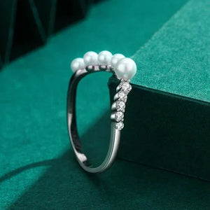 Silver ring with pearls on a green background