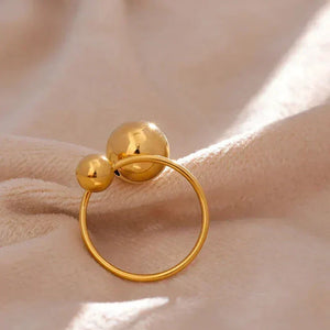 18K gold-plated ring with two polished spheres on a soft beige fabric background
