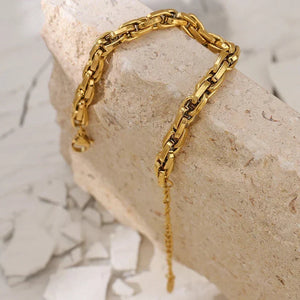 Gold chain bracelet on a stone surface with a marble background