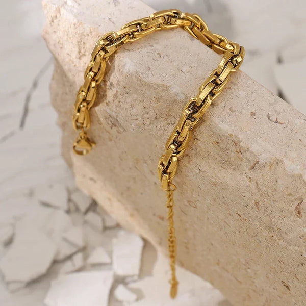 Gold chain bracelet on a stone surface with a marble background