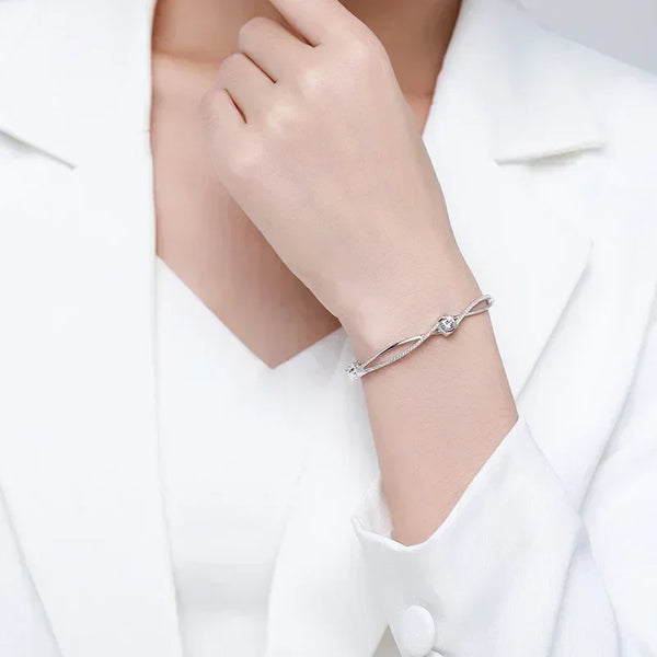 Elegant woman wearing a sterling silver bracelet with a heart charm, white outfit background