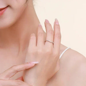 Elegant woman wearing a thin silver ring with small stones on her finger, close-up.