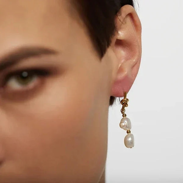 Pearl earring worn by a person on a plain background