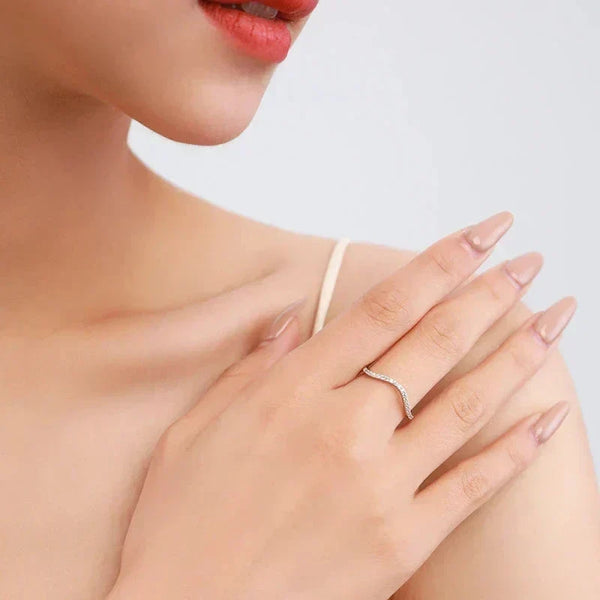 Woman wearing delicate silver wave ring with cubic zirconia accents on her finger