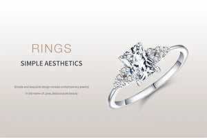 Elegant silver engagement ring with a rectangular clear center stone and side accents.