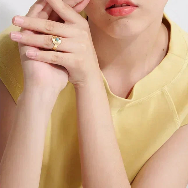 Woman wearing gold-plated gemstone ring, styled with minimalist yellow top