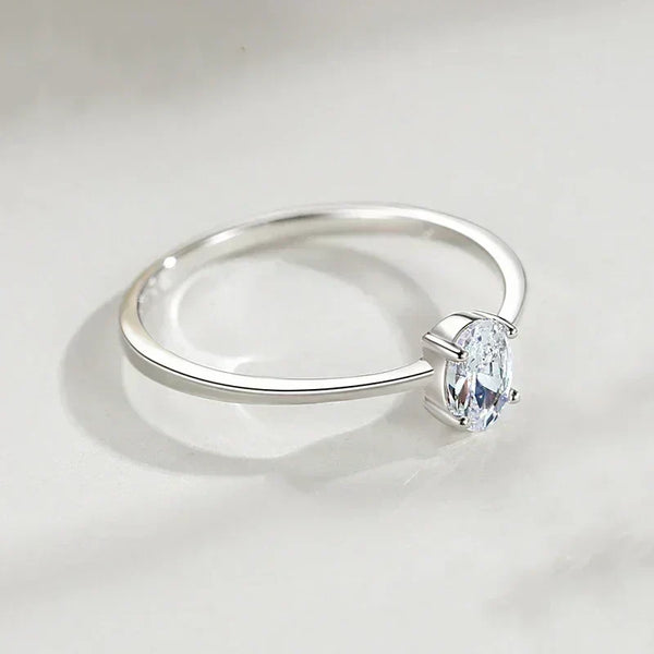 Sterling silver solitaire ring with oval-cut clear gemstone on a white surface