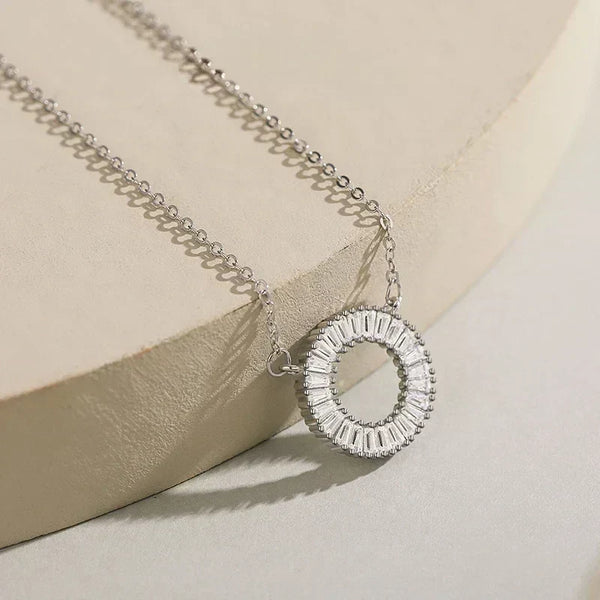 Silver necklace with a circular pendant on a beige surface