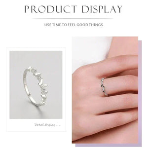 Silver ring with decorative elements displayed on a hand against a white background