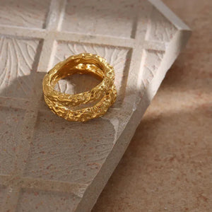 Textured gold-plated ring with organic design on stone surface, elegant women's jewelry