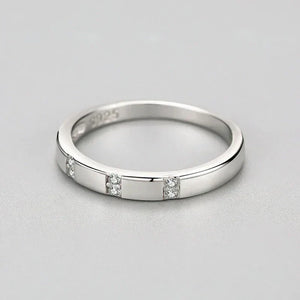 Silver ring with small diamonds on a light gray background
