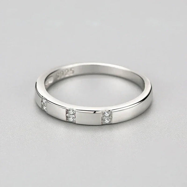 Silver ring with small diamonds on a light gray background