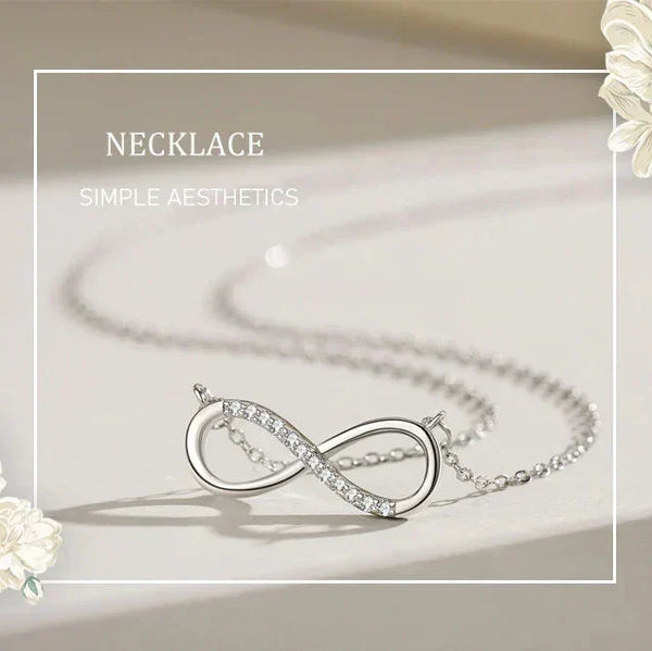 Silver infinity necklace on a light background with floral elements