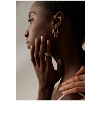 Woman wearing gold-plated drop hoop earrings and chunky gold chain ring