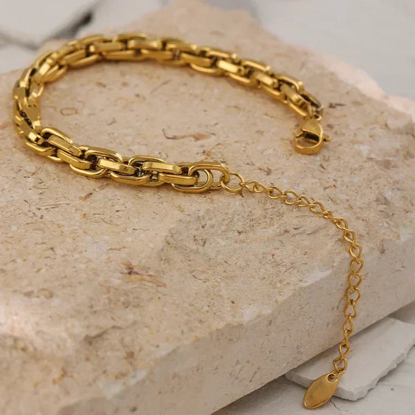 Gold chain bracelet on a textured stone surface