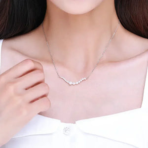 Woman wearing a delicate 925 silver necklace with small pearls, elegant jewelry close-up