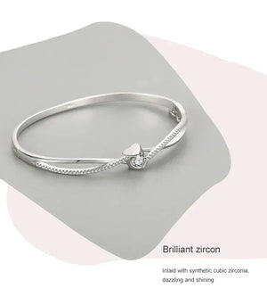 Sterling silver bracelet with heart and cubic zirconia centerpiece on gray background