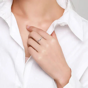 Woman wearing a delicate 925 silver ring with small round stones, styled with a white shirt.