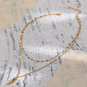 Gold necklace with small black stones on a textured surface