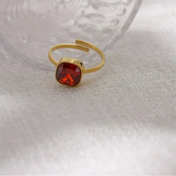 18K gold-plated open ring with square red gemstone on textured white fabric