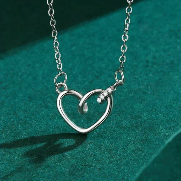 Silver heart-shaped necklace with a small pendant on a green background