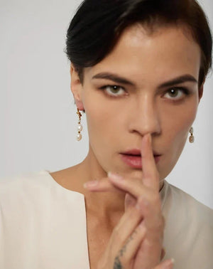 Woman with a finger on her lips against a plain background