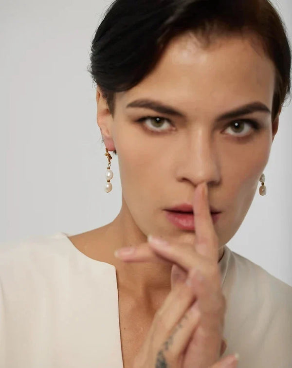 Woman with a finger on her lips against a plain background