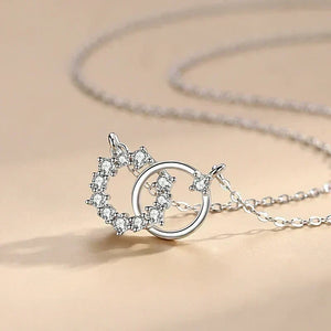Silver necklace with a heart and circle pendant on a beige background
