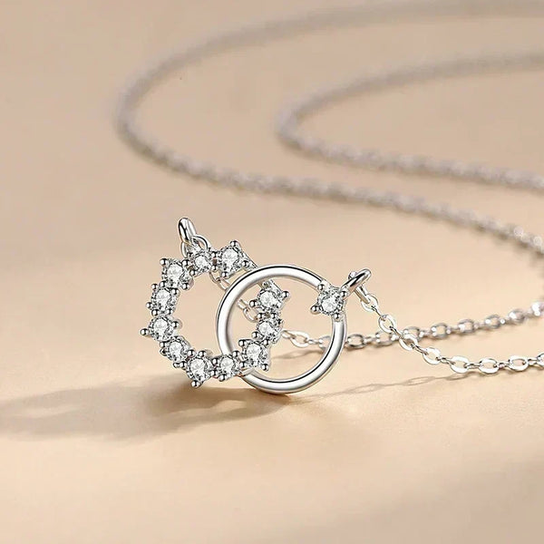 Silver necklace with a heart and circle pendant on a beige background