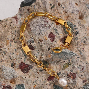 Gold bracelet with a pearl on a textured stone surface
