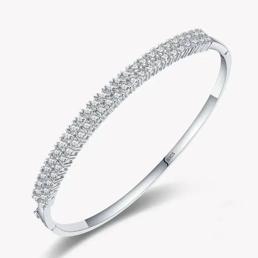 Sterling silver bangle with three rows of sparkling cubic zirconia stones on white background
