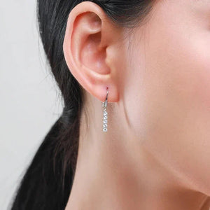 Close-up of an ear wearing a silver earring with a blurred background