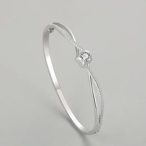 Silver bracelet with a central diamond on a light gray background