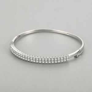 Sterling silver bangle with three rows of sparkling cubic zirconia stones on a grey background
